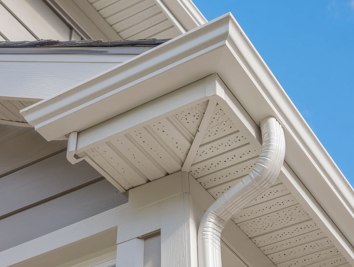 White gutter guard system, fascia, drip edge, soffit, and downspout strap with horizontal vinyl siding